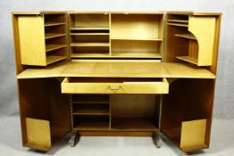 A mid century vintage teak Newcraft & Co. office in a box, fitted cabinet with doors opening to