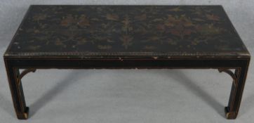 A black lacquered low table with all over scrolling foliate decoration. H.38 L.108 W.54cm