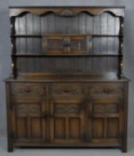 A mid century Jacobean style country oak dresser with upper open plate rack above an arrangement