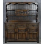 A mid century Jacobean style country oak dresser with upper open plate rack above an arrangement