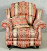 A contemporary upholstered armchair on turned supports terminating in brass cup casters. H.100 W.100