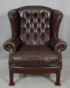 A Georgian style wing back armchair by Christie Tyler in deep buttoned leather studded upholstery on