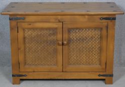 An Eastern teak brass bound side cabinet with rattan panelled doors on block feet. H.62 W.95 D.47.
