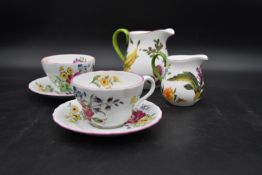 A pair of large Spode floral decorated tea cups and saucers and two Royal Collection jugs. H.14 W.