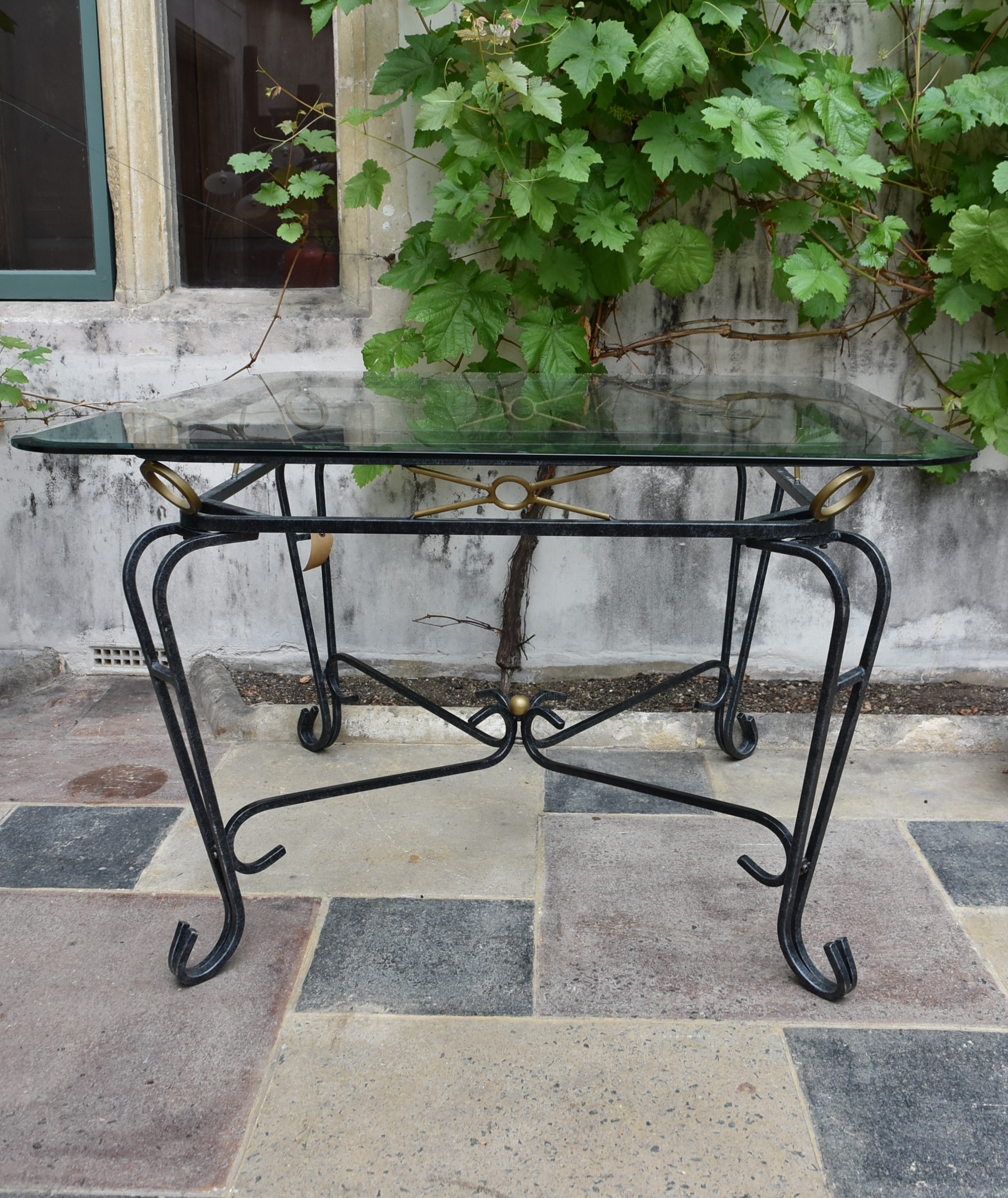 A wrought iron conservatory dining table with bevelled plate glass top. H.73 W.115cm