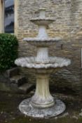 A weathered cast reconstituted stone three tier garden fountain with scrolling edges to the bowls on