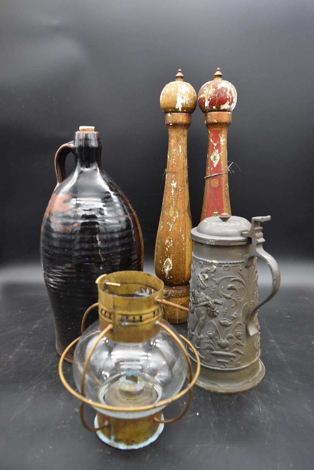 A pewter lidded tankard with relief decoration, a stoneware flagon, a lamp and large wooden pepper