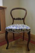 A Victorian carved mahogany balloon back side chair with foliate upholstered stuffover seat on