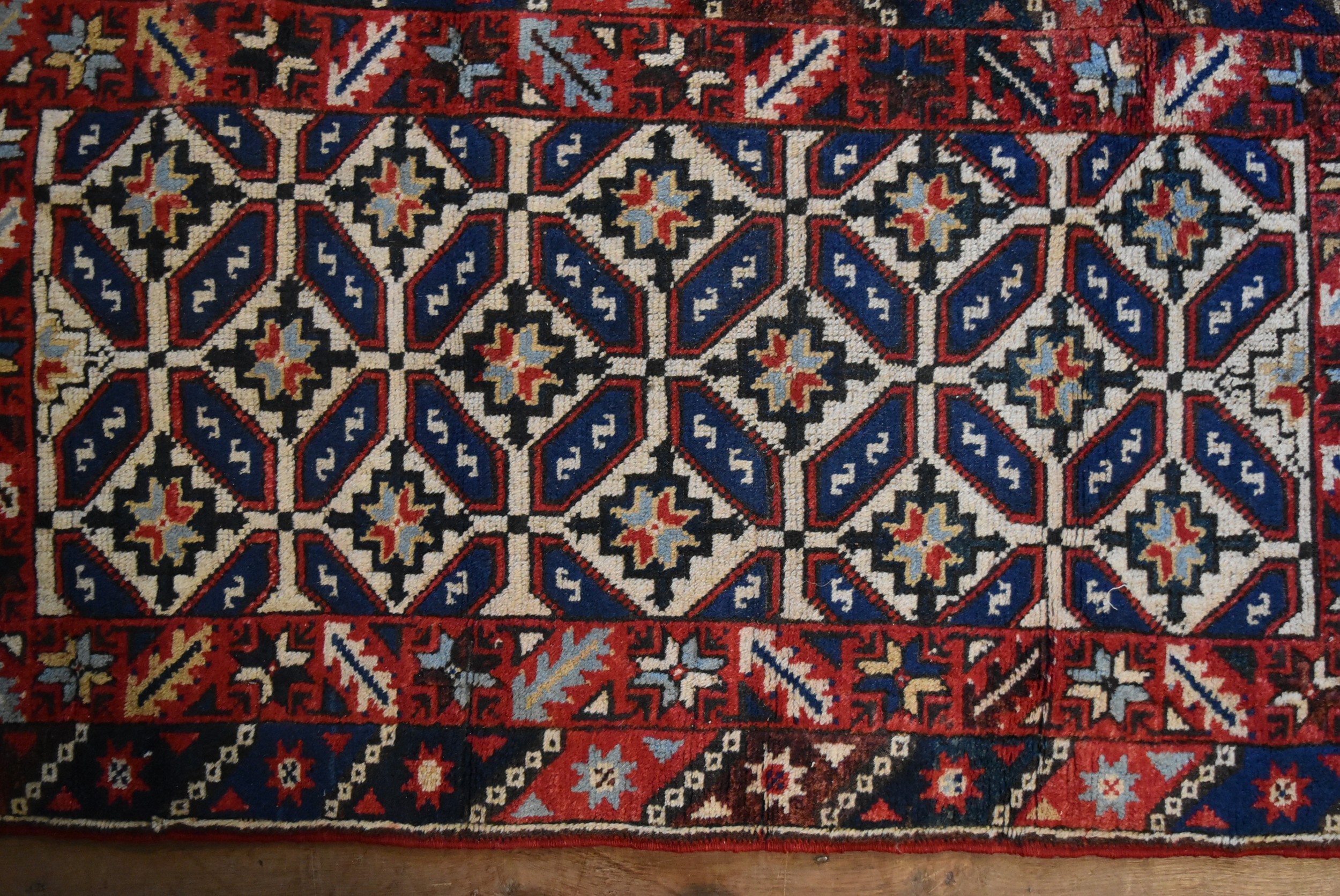 A Kazak rug with repeating stylised flowerhead motifs across the field contained by serrated palm - Image 2 of 4