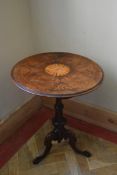 A 19th century burr walnut occasional table with central inlaid paterae raised on carved tripod