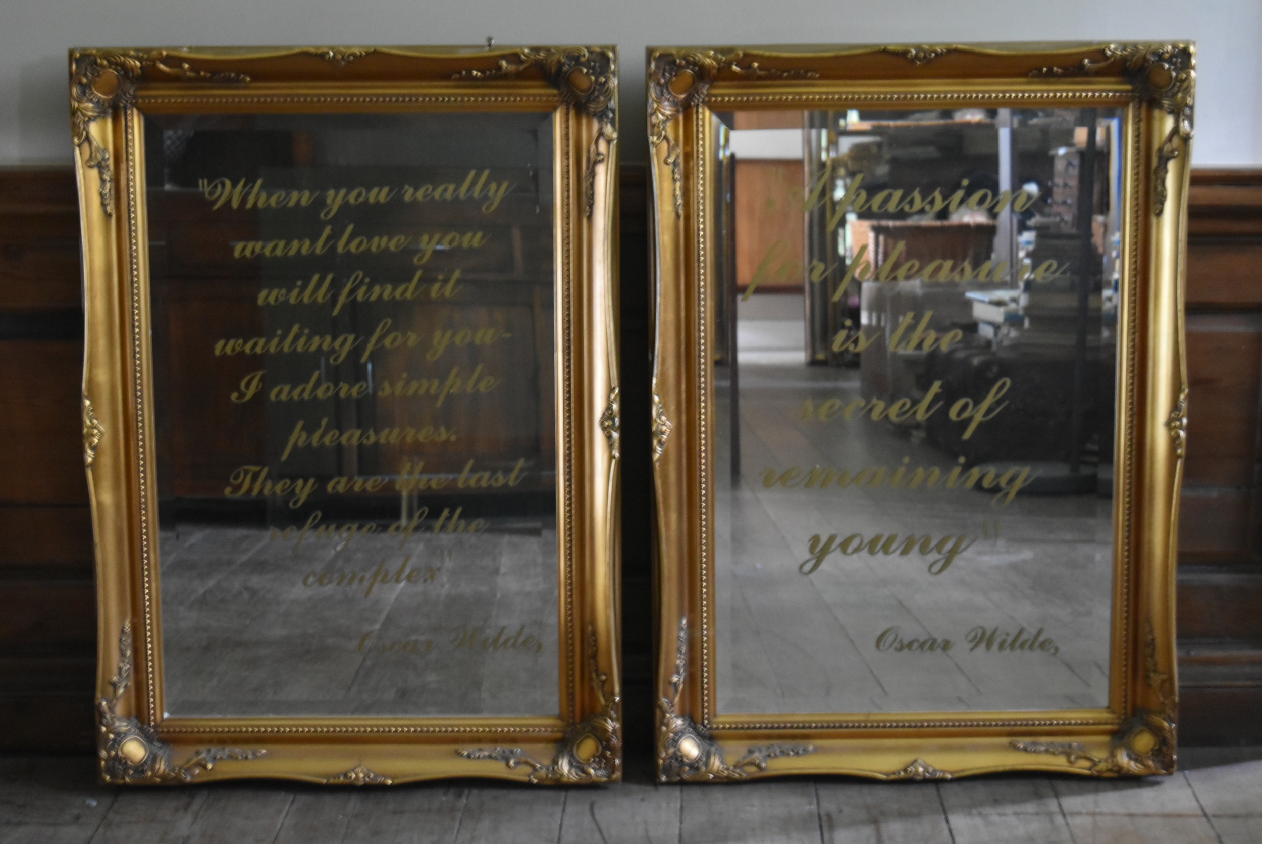 A pair of Rococo scroll gilt framed wall mirrors with bevelled plates each bearing an Oscar Wilde