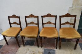 A set of four late 19th century walnut dining chairs with profuse ebony and satinwood inlay to the