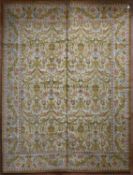 A vintage Spanish carpet with repeating scrolling floral design across the fawn field enclosed by