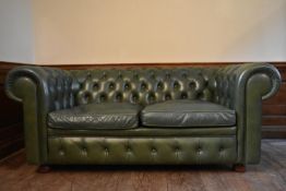 A two seater Chesterfield sofa in deep buttoned leather upholstery on bun feet. H.70 W.170 D.80cm