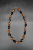 A vintage plastic necklace comprising of amber and black faceted beads. L.43cm