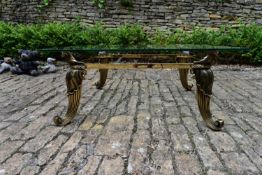 A contemporary Egyptian Revival heavy brass coffee table with plate glass top on reeded scroll