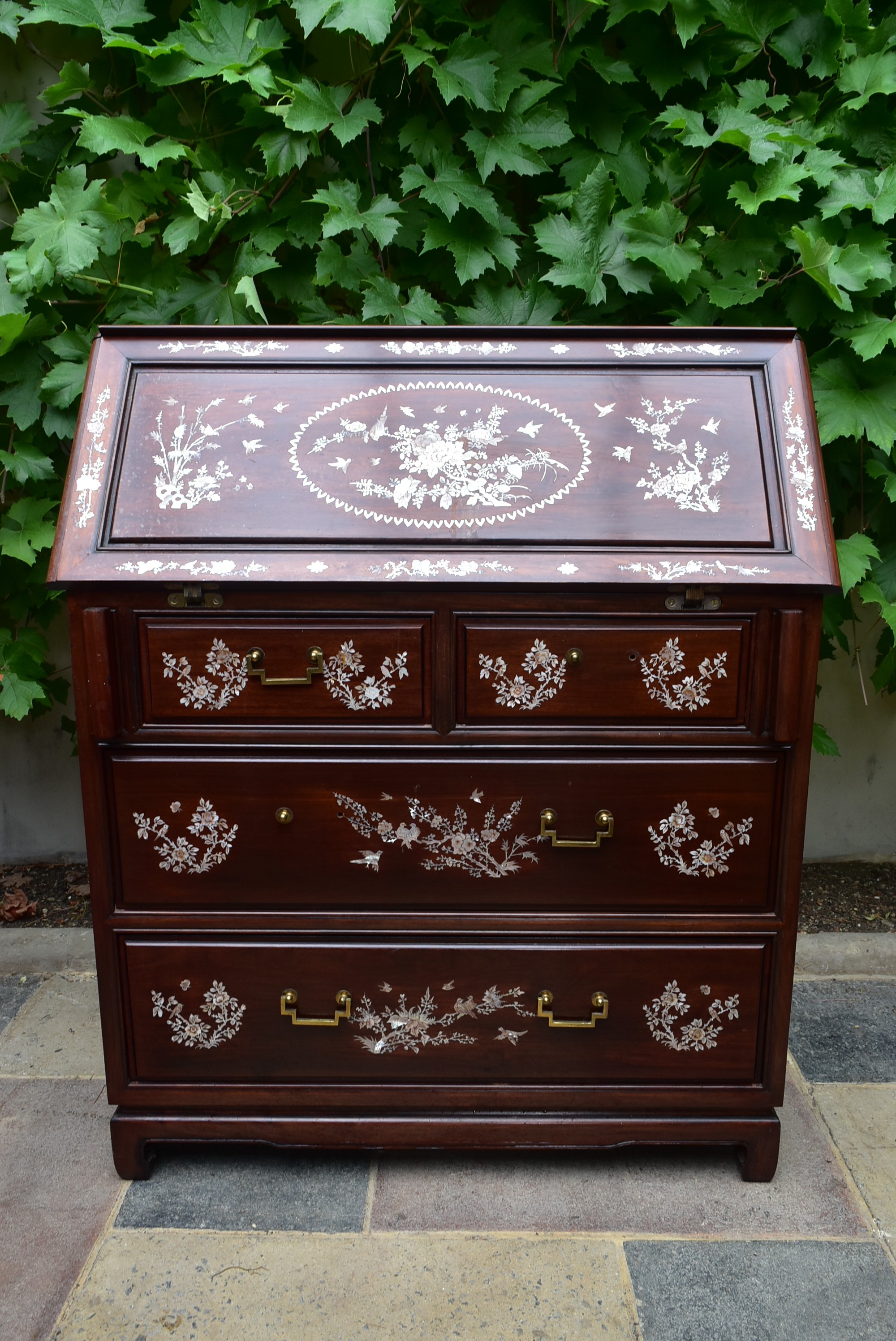 A Chinese hardwood bureau with fall front revealing fitted interior and with profuse all over mother