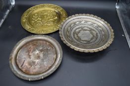 An eastern pierced metal bowl on tripod feet along with two other metal plates. H.6 Dia.35cm (with