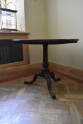 A Georgian mahogany tilt top table with central turned pedestal on tripod cabriole pad foot