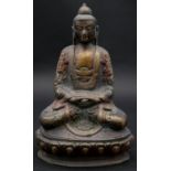 An oriental 20th century painted brass Buddha statue in lotus position sitting among lotus petals.