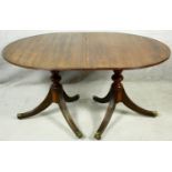 A Georgian style mahogany dining table with extra leaf on twin pedestal reeded swept supports