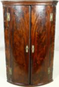 A Georgian flame mahogany bow fronted corner cabinet with original brass work. H.108 W.68 D.46cm