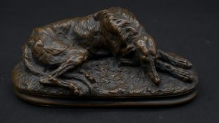 A bronze figure of a resting greyhound on a naturalistic base. L.15cm
