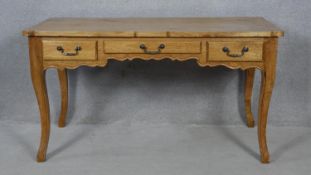 A French Provincial fruitwood Louis XV style bureau plat with three frieze drawers raised on slender