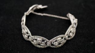 An Art Deco marcasite set silver pierced floral design articulated bracelet with push clasp and