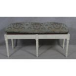 A painted Continental style stool with floral upholstered squab cushion. H.55 L.110 W.45cm