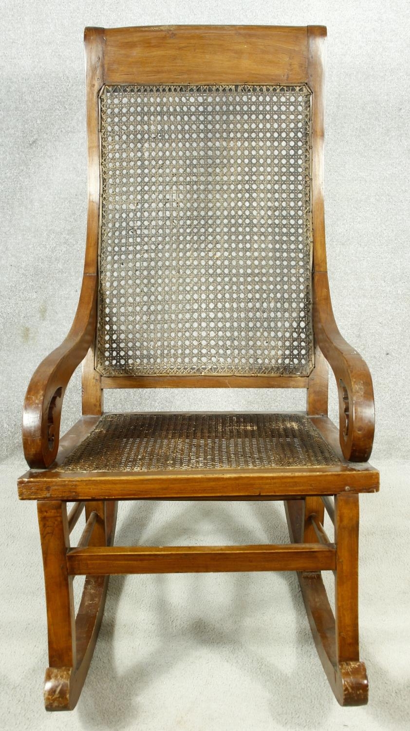 A 19th century Colonial style teak rocking chair with caned back and seat. H.111cm