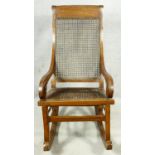 A 19th century Colonial style teak rocking chair with caned back and seat. H.111cm