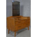 A mid century vintage teak dressing table with adjustable bevelled plate mirror above an arrangement