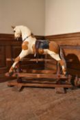 An early 20th century carved and painted rocking horse on swing pedestal base. H.89 W.92 D.23cm