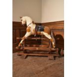 An early 20th century carved and painted rocking horse on swing pedestal base. H.89 W.92 D.23cm