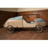 An early 20th century push along toy racing car of sheet metal on a wooden frame. H.56 W.160 D.42cm