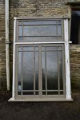 A large painted hardwood window frame of twenty seven double glazed panels with stained glass corner