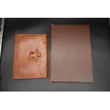 A vintage leather fronted stationary blotting pad along with a tan leather stationary folder with