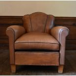 A vintage club armchair in piped and studded tan leather upholstery on block supports. H.82 W.78 D.