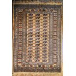 A Bokhara style rug with repeating gul motifs on a sand ground within stylised flowerhead multiple