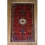 A Persian rug with central star medallion on a burgundy ground decorated with stylised foliate