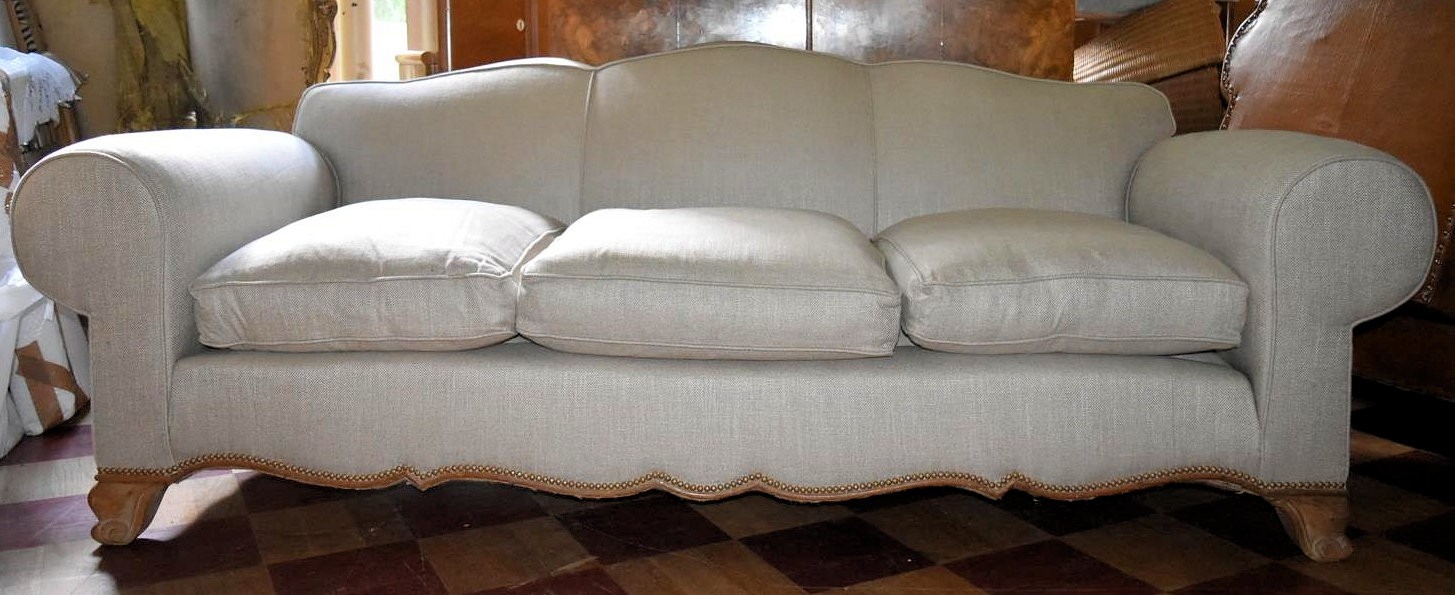 A three seater sofa with shaped back and apron upholstered in piped and studded calico on carved