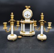 A French neoclassical style clock garniture in gilt metal and marble with a pair of three branch