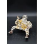 A vintage metal figure of a seated Michelin Man. H.13 W.17cm