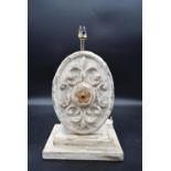 A painted metal table lamp with Fleur de Lys cartouche to one side on stepped distressed painted