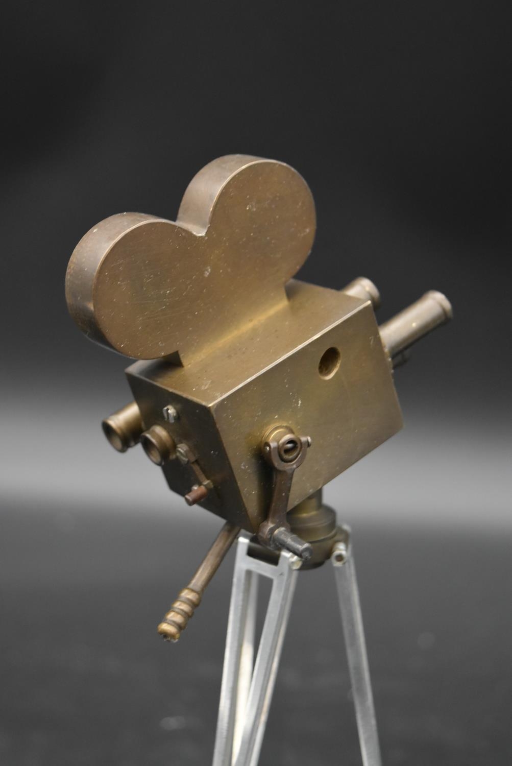 A brass and metal model of a 1930's film camera with hinged head on tripod base standing on wooden - Image 4 of 4