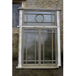 A large painted hardwood window frame of twenty nine double glazed panels with stained glass