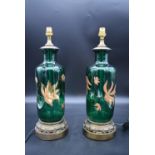 A pair of green glass table lamps with painted lotus flower decoration on gilt metal acanthus bases.