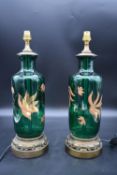 A pair of green glass table lamps with painted lotus flower decoration on gilt metal acanthus bases.