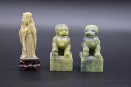 A pair of Chinese carved jade Foo dogs on square bases along with a carved jade immortal on